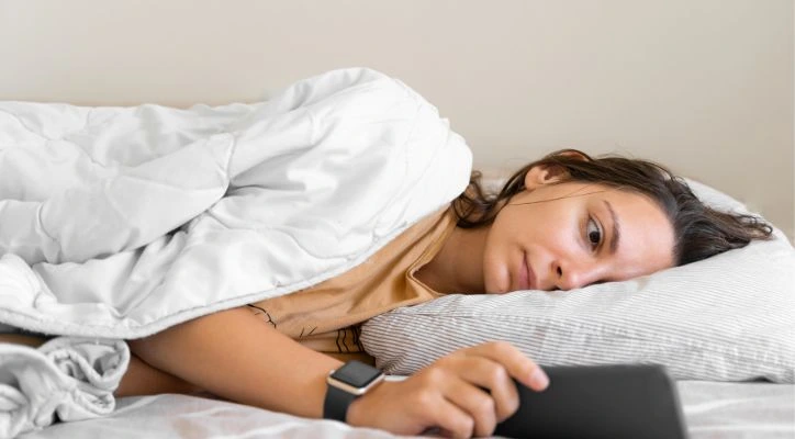 A woman in bed looking at her cellphone app