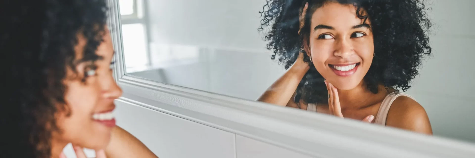 woman looking at her skin at the mirror