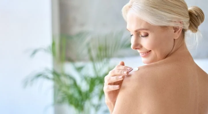 woman applying skin care product on her body