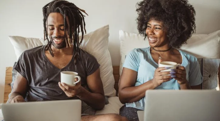 man and a woman drinking coffee in the front of laptop