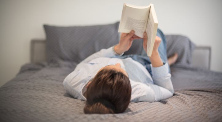lady reading a book while on bed