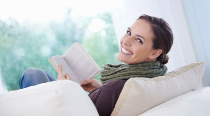 lady is smiling while reading a book